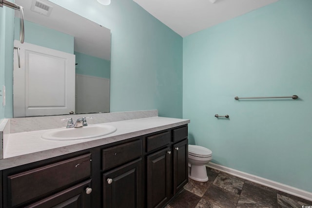 bathroom featuring visible vents, toilet, stone finish flooring, vanity, and baseboards