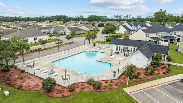 community pool featuring a patio area, a fenced backyard, a residential view, and an outdoor structure