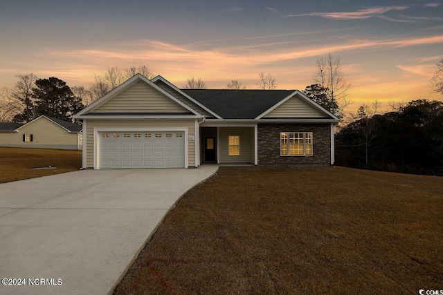 ranch-style home featuring driveway, a yard, an attached garage, and stone siding