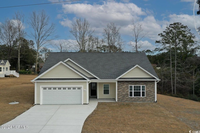 view of front of property featuring a garage, concrete driveway, a shingled roof, and a front lawn