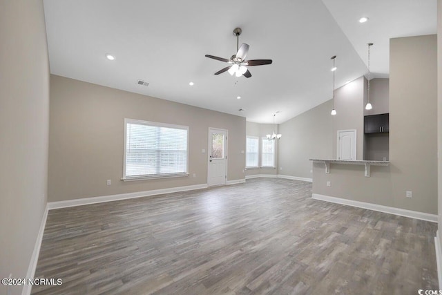 unfurnished living room featuring lofted ceiling, ceiling fan with notable chandelier, wood finished floors, visible vents, and baseboards