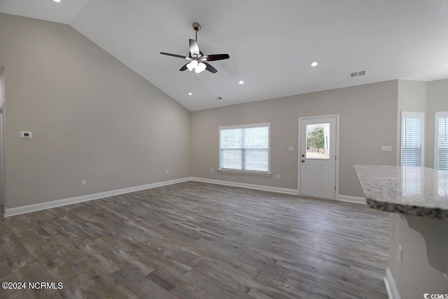 unfurnished living room featuring baseboards, visible vents, dark wood finished floors, lofted ceiling, and ceiling fan