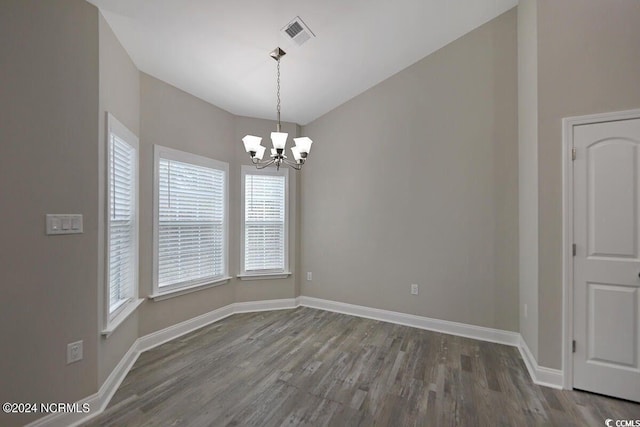 empty room with wood finished floors, visible vents, baseboards, and an inviting chandelier