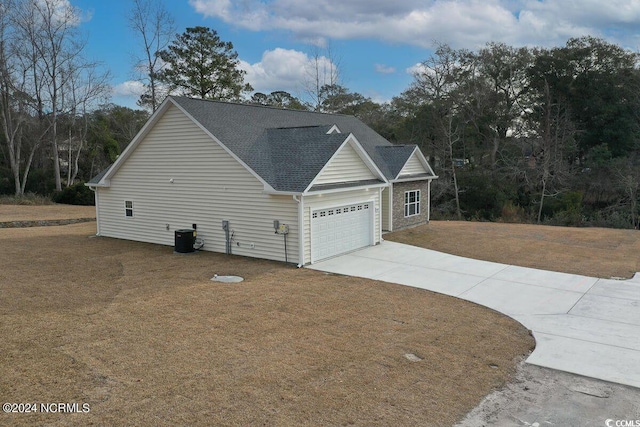 view of side of property with a garage, driveway, a lawn, and roof with shingles