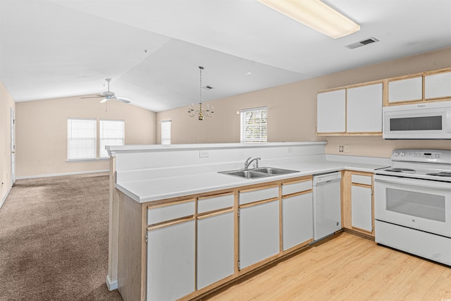 kitchen featuring visible vents, a peninsula, plenty of natural light, white appliances, and a sink