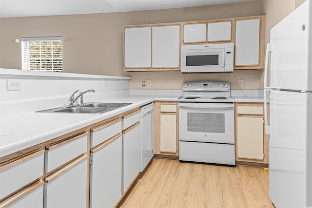 kitchen featuring white appliances, light countertops, light wood-style floors, and a sink