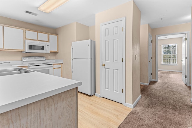 kitchen with light countertops, a sink, white appliances, visible vents, and light wood-style floors