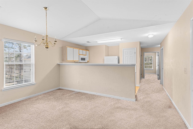empty room with light colored carpet, lofted ceiling, baseboards, and an inviting chandelier