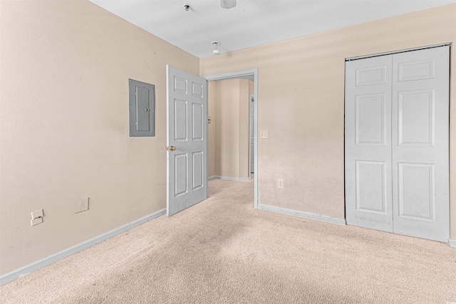 unfurnished bedroom with a closet, baseboards, electric panel, and carpet