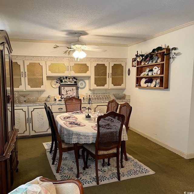 dining space featuring a textured ceiling, ceiling fan, baseboards, dark colored carpet, and crown molding