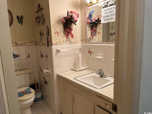 bathroom with toilet, tile walls, vanity, wainscoting, and tile patterned floors