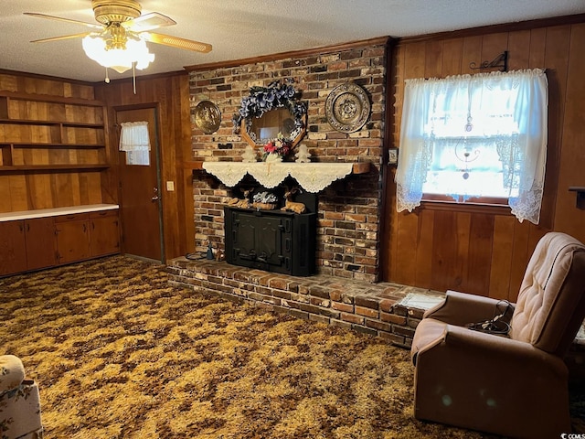 living room featuring a textured ceiling, wooden walls, carpet flooring, ornamental molding, and a brick fireplace