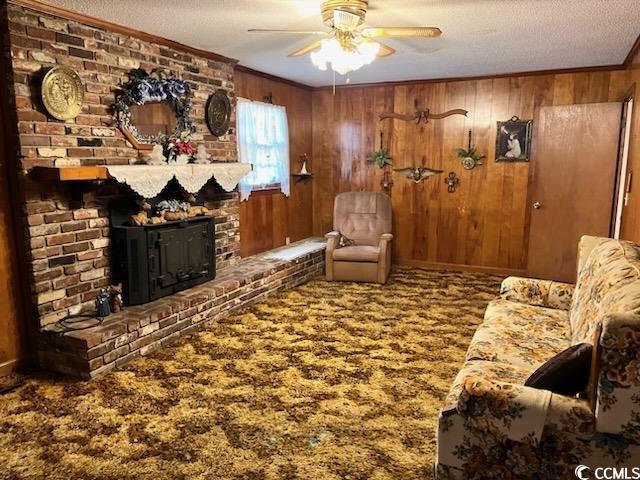 living room with carpet floors, wood walls, and ornamental molding