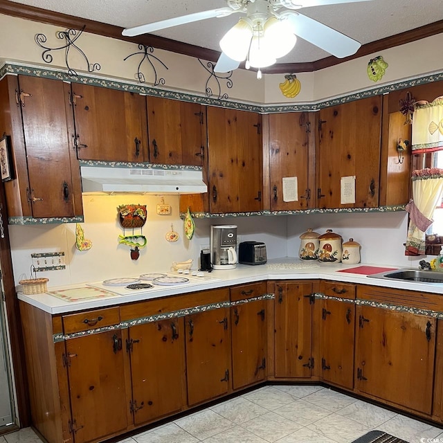 kitchen featuring brown cabinetry, light countertops, and under cabinet range hood