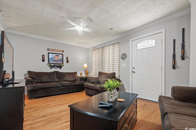 living room with a textured ceiling, visible vents, a ceiling fan, light wood-type flooring, and crown molding