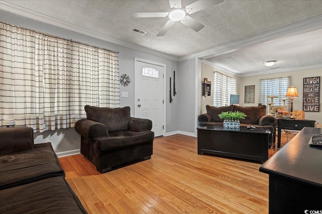 living area with crown molding, visible vents, light wood-style flooring, a ceiling fan, and a textured ceiling