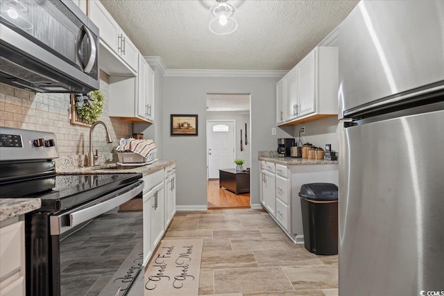 kitchen with crown molding, stainless steel appliances, decorative backsplash, white cabinets, and a textured ceiling