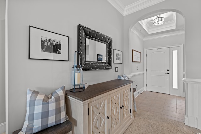 entryway with arched walkways, ornamental molding, light tile patterned floors, and a raised ceiling