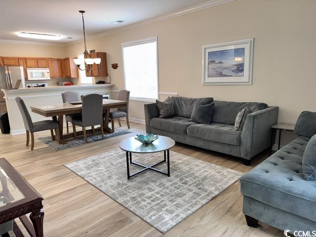 6253 Catalina Dr Unit 921, North Myrtle Beach, SC 29582 - living room featuring ornamental molding, light wood-style flooring, a chandelier, and baseboards