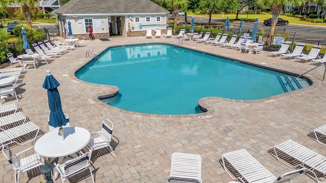 community pool with an outbuilding, fence, and a patio