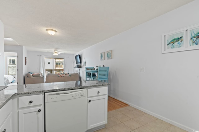 kitchen with white dishwasher, white cabinetry, open floor plan, and light stone counters