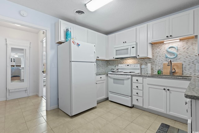 kitchen with light tile patterned floors, white appliances, a sink, visible vents, and light stone countertops