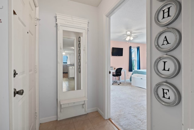 corridor with light carpet, light tile patterned floors, and baseboards