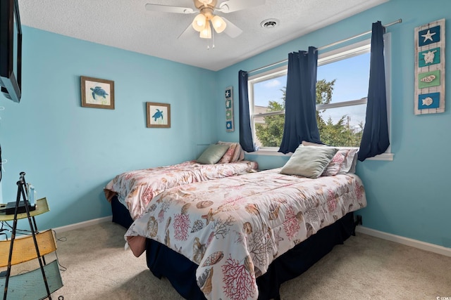 carpeted bedroom with a textured ceiling, a ceiling fan, visible vents, and baseboards