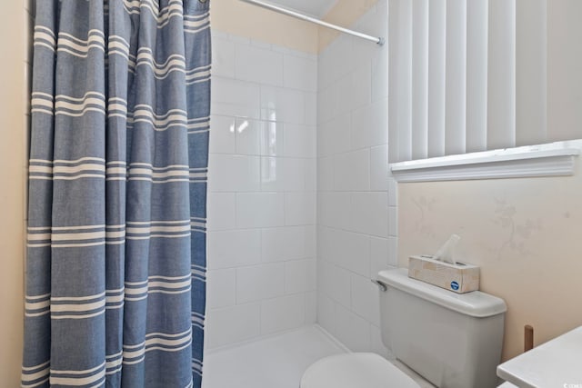 bathroom with tiled shower and toilet