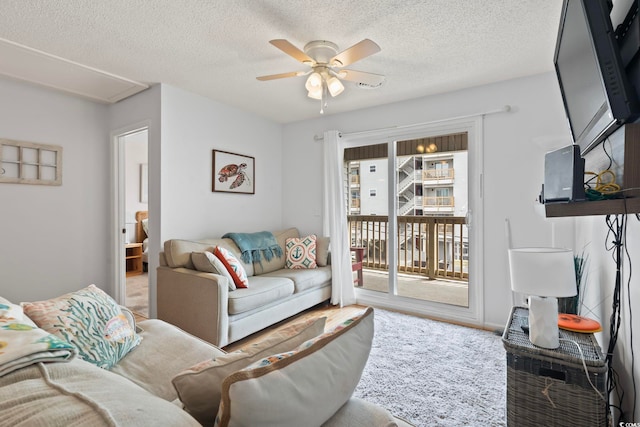 living area with a ceiling fan and a textured ceiling