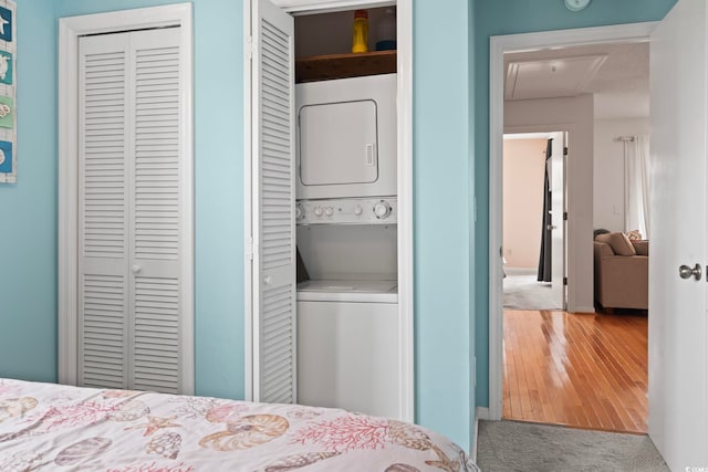 bedroom featuring carpet floors and stacked washer / drying machine