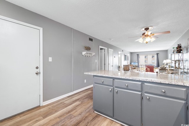 3308 S Ocean Blvd Unit 2-A, North Myrtle Beach, SC 29582 - kitchen with gray cabinetry, light wood-type flooring, a textured ceiling, a ceiling fan, and open floor plan