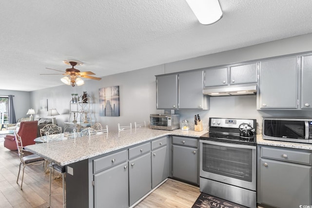 3308 S Ocean Blvd Unit 2-A, North Myrtle Beach, SC 29582 - kitchen with appliances with stainless steel finishes, gray cabinetry, a peninsula, under cabinet range hood, and a textured ceiling