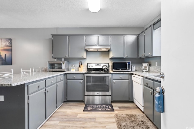 3308 S Ocean Blvd Unit 2-A, North Myrtle Beach, SC 29582 - kitchen featuring stainless steel appliances, under cabinet range hood, a peninsula, gray cabinetry, and light wood finished floors