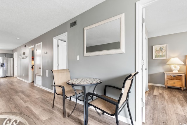 3308 S Ocean Blvd Unit 2-A, North Myrtle Beach, SC 29582 - dining space with light wood-style flooring, baseboards, and a textured ceiling