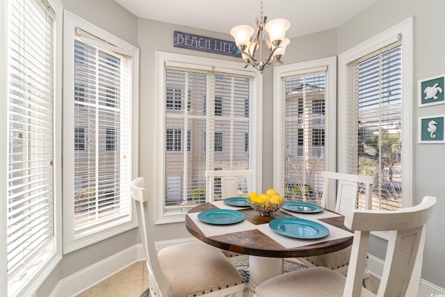 tiled dining space featuring a notable chandelier, baseboards, and a healthy amount of sunlight