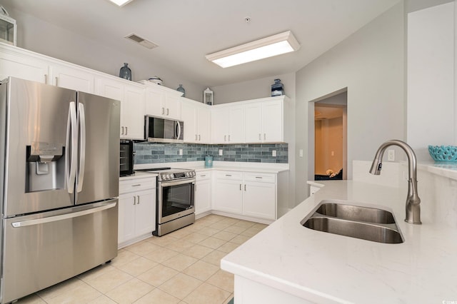 kitchen featuring stainless steel appliances, a sink, visible vents, white cabinetry, and backsplash