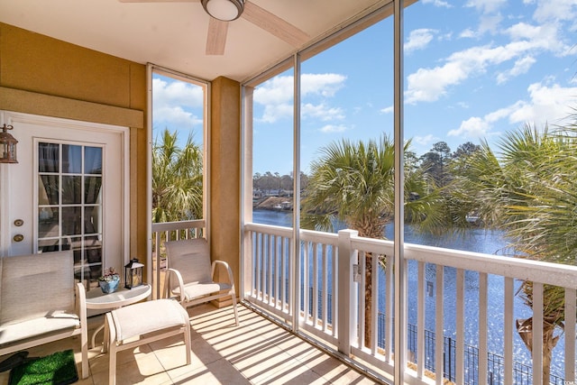 sunroom / solarium featuring a ceiling fan and a water view