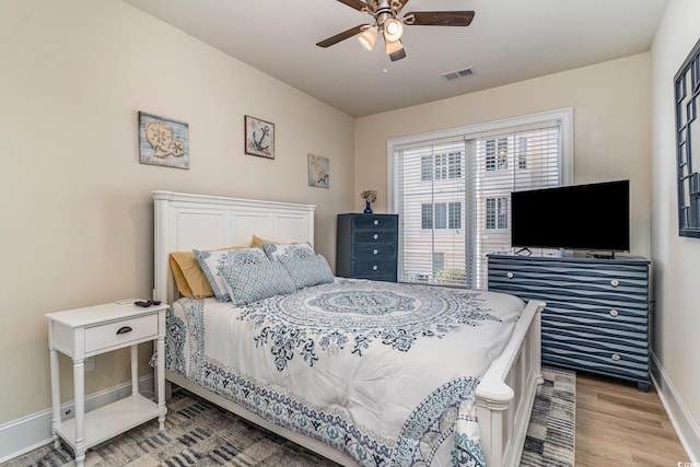 bedroom featuring visible vents, baseboards, ceiling fan, and wood finished floors