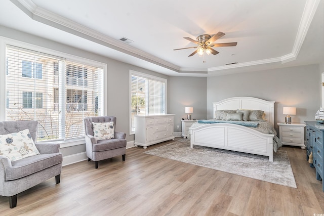 bedroom featuring light wood-style flooring, visible vents, a tray ceiling, and baseboards