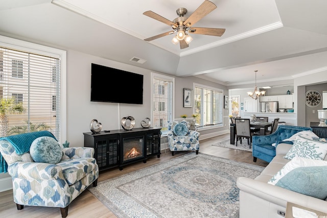 living room with light wood finished floors, visible vents, crown molding, and a glass covered fireplace