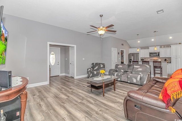 living room with light wood-type flooring, visible vents, vaulted ceiling, and baseboards