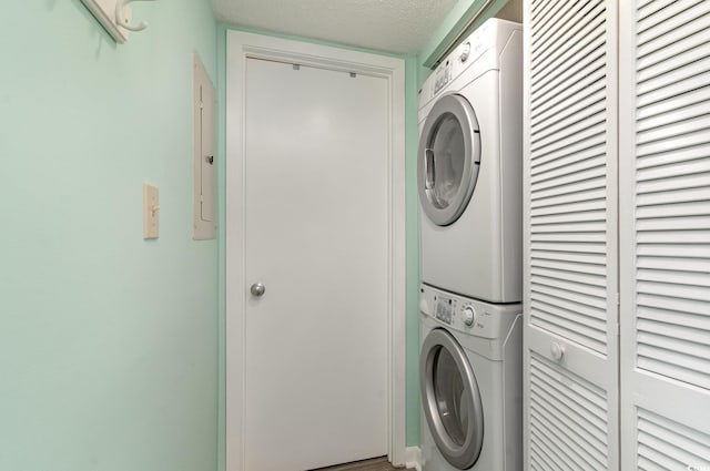 laundry area with a textured ceiling and stacked washing maching and dryer