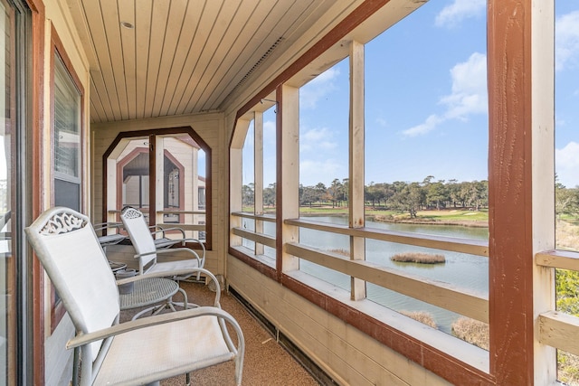 sunroom with wood ceiling and a water view