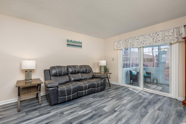 living area with a textured ceiling, baseboards, and wood finished floors