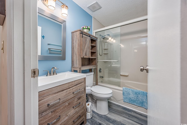 full bath with toilet, wood finished floors, combined bath / shower with glass door, a textured ceiling, and vanity