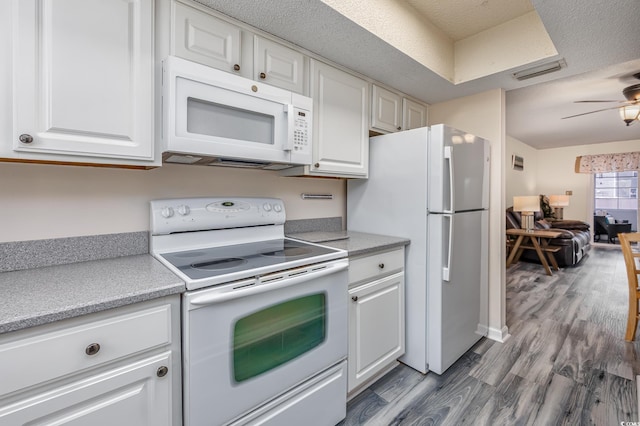 kitchen with white cabinets, white appliances, light countertops, and wood finished floors