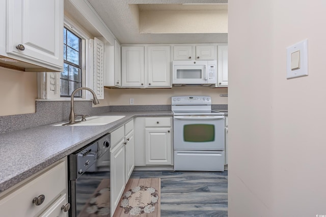 kitchen with white appliances, dark wood-style flooring, a sink, and white cabinetry