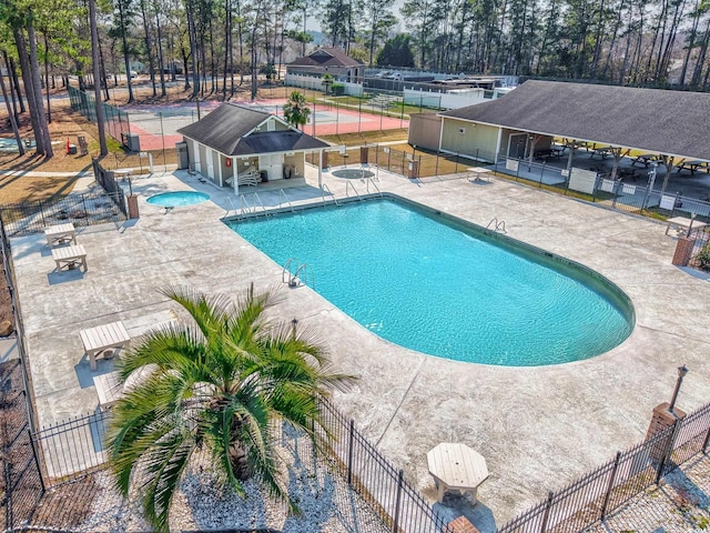 pool with a patio area, fence, and a hot tub