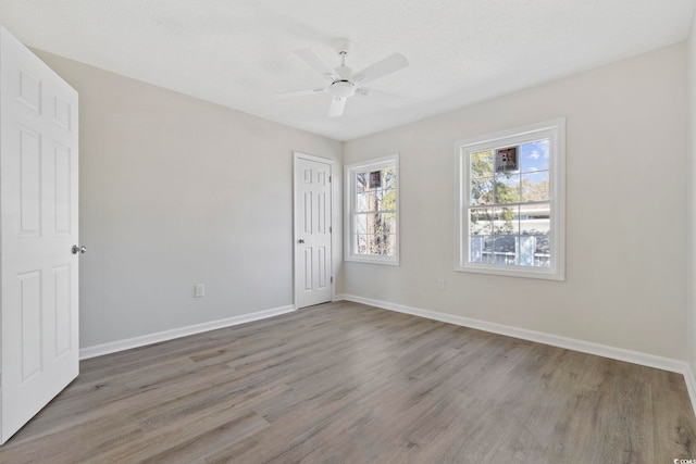 empty room featuring ceiling fan, a textured ceiling, wood finished floors, and baseboards